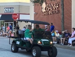 L. B. Eckelkamp, Jr. and Bonnie Eckelkamp on Bank of Washington golf cart in front of Downtown branch during Washington Town and Country Fair parade